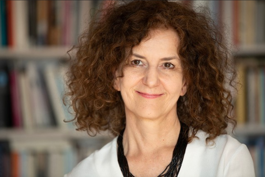 Portrait von Dera Loher mit lockigen langen braunen Haaren und einem weissen Pulli