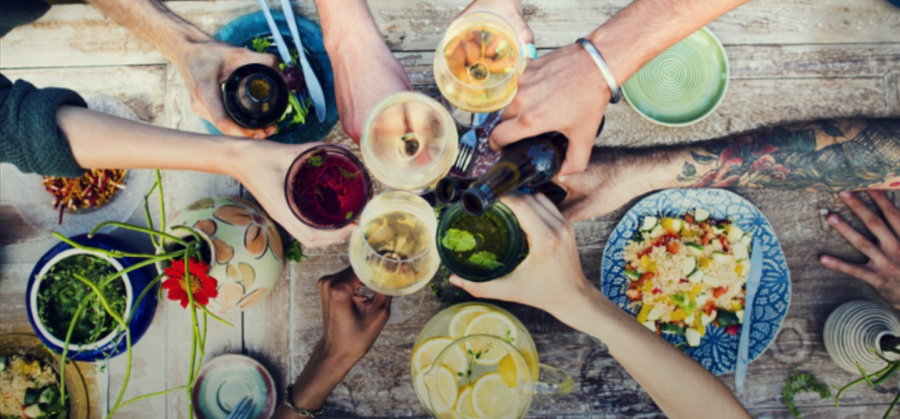 man sieht hände von Menschen aus verschiedenen Ländern, die mit verschiedenen Drinks einander zuprosten.