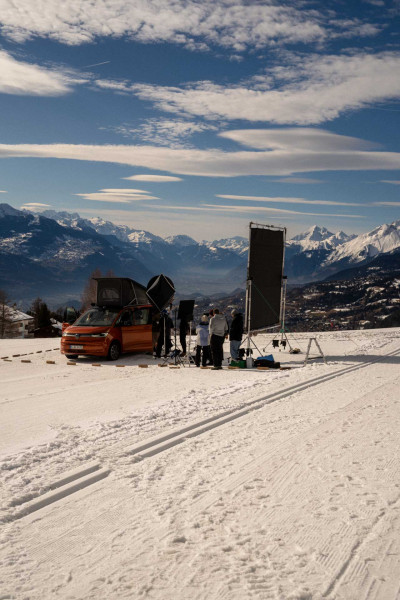 Équipe de tournage et projecteurs autour d'un van Volkswagen California sur le golf de Crans-Montana enneigé, pour Volkswagen International.