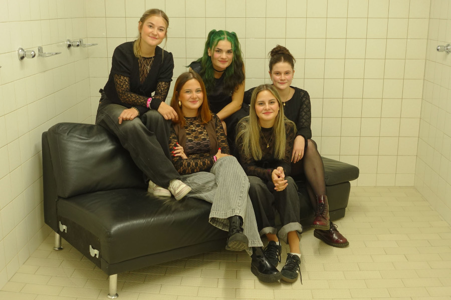 Die fünf jungen Frauen von Mainstreet47 sitzen zusammen auf einem schwarzen Sofa