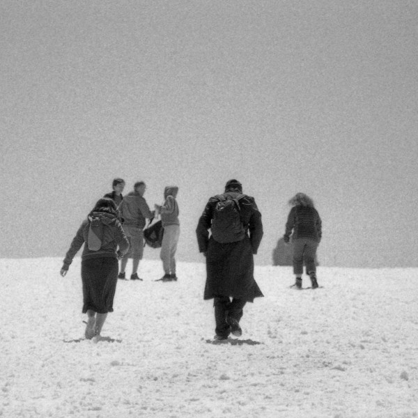 6 personnes photographiées de dos, avançant sur un chemin de neige