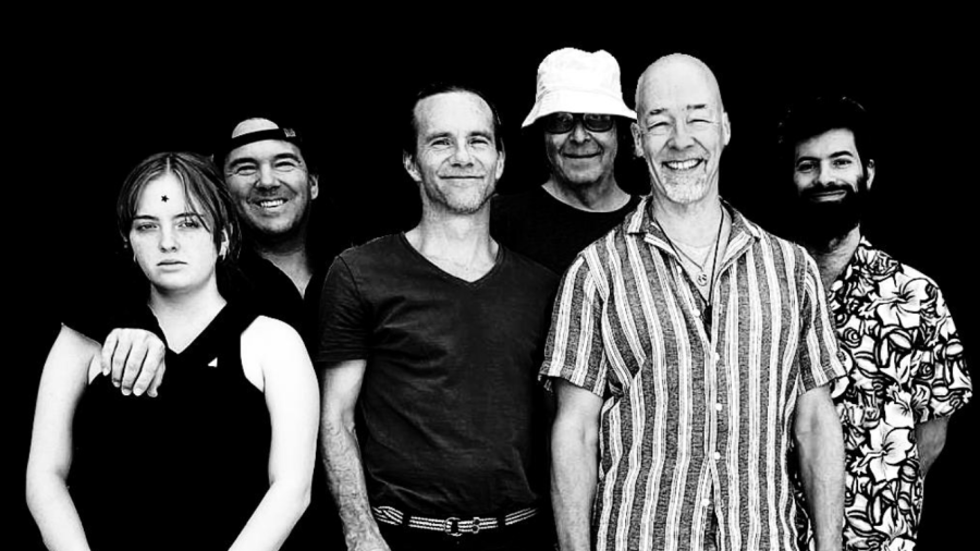 Die Band schaut lächelnd in die Kamera. Es sind 5 Männer und eine Frau. 